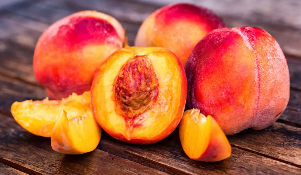Fresh ripe peaches and slices on wooden table
