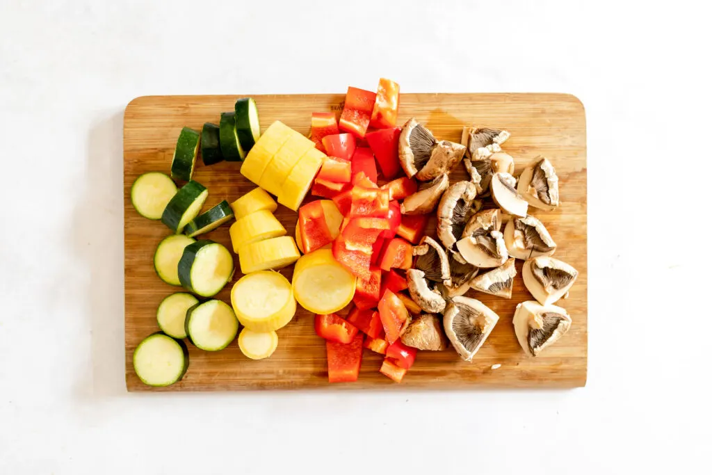 sliced zucchinis, red bell pepper, mushrooms on chopping board