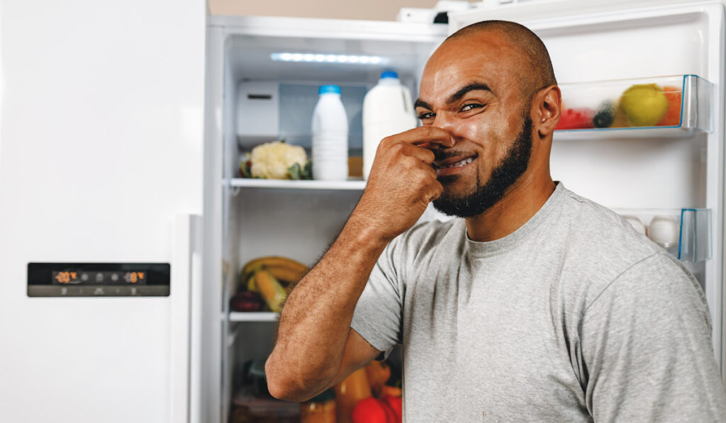  man closing nose because of bad smell from fridge