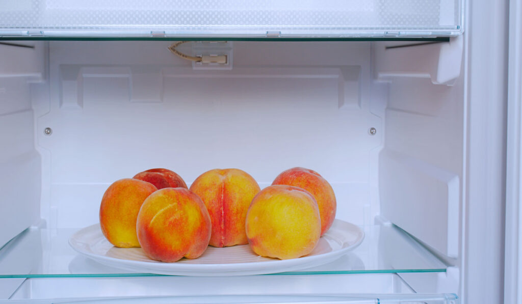 ripe peaches on white plate inside refrigerator