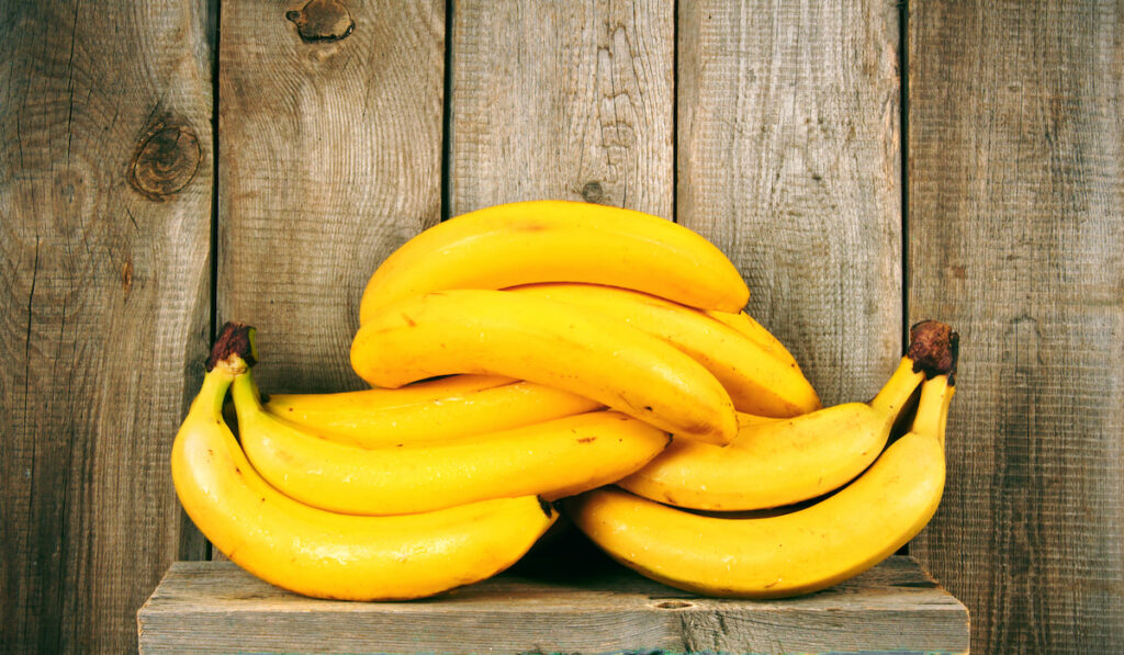 Fresh bananas on wooden shelf.

