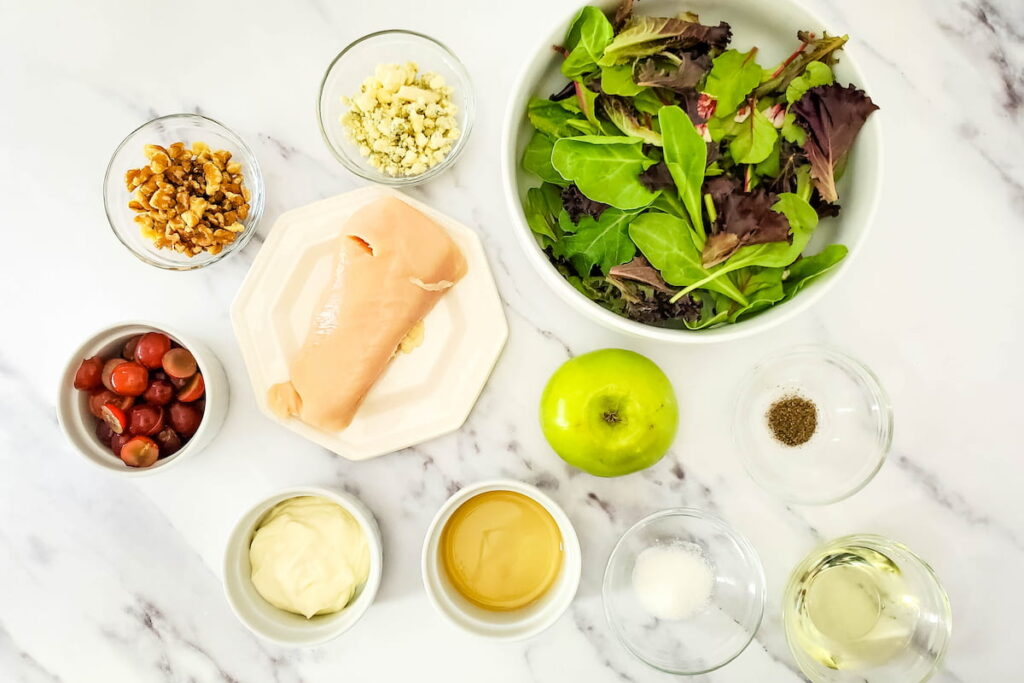 Ingredients for Chicken and Apple House Salad laid on a marble table