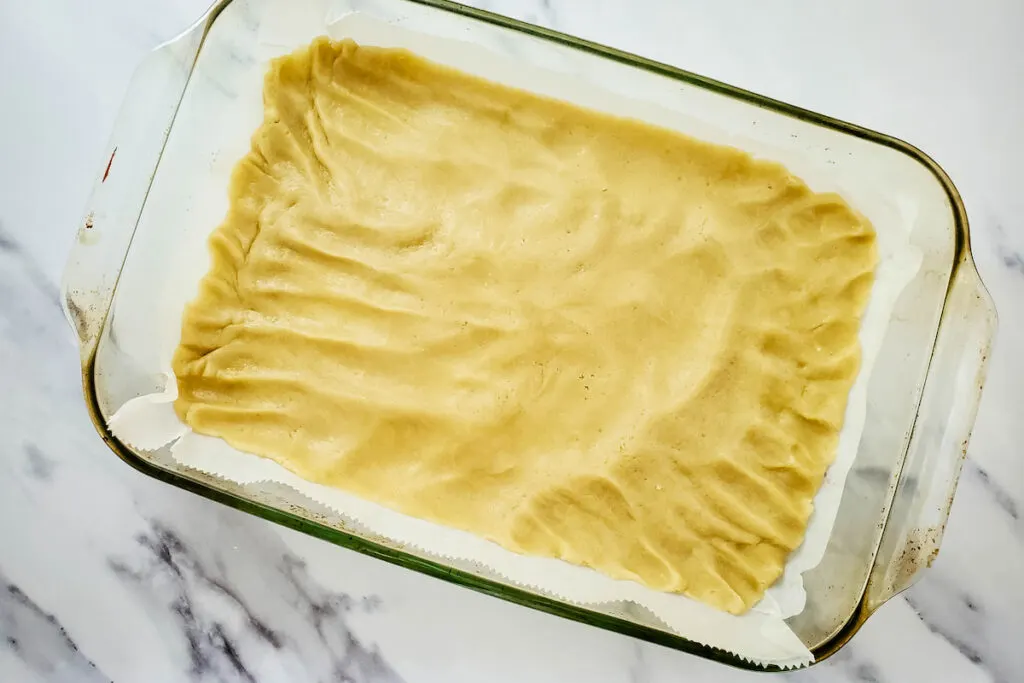 Pressed cookie dough on top of the parchment paper in the cake pan