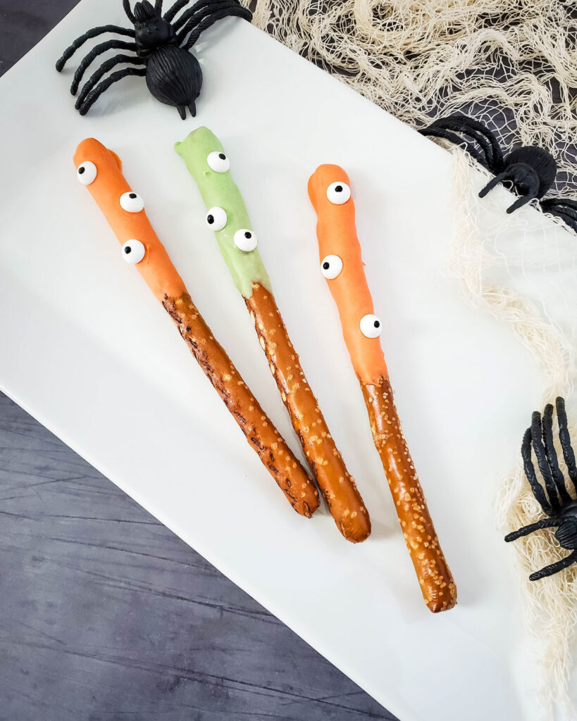 3 pieces Halloween Monster Pretzels on white rectangular plate with black spiders and web on the side