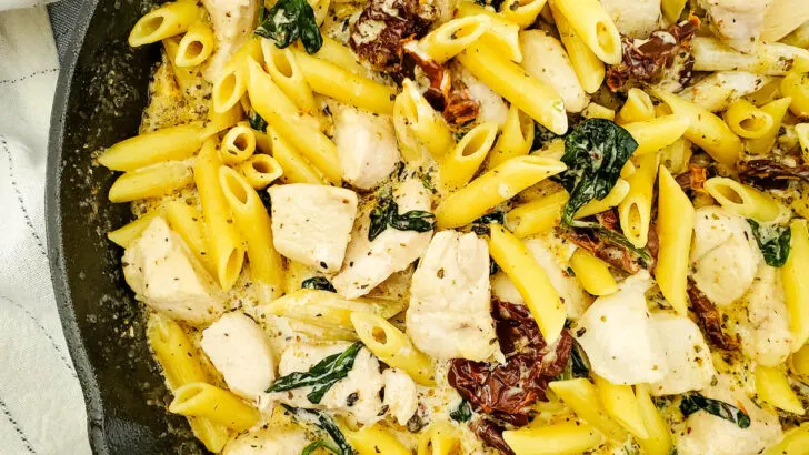 Tuscan Chicken Pasta in cast iron skillet with cloth on the table