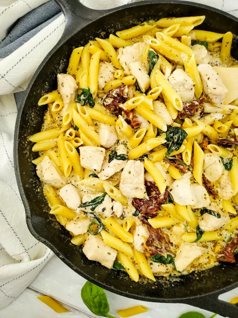 Tuscan Chicken Pasta in cast iron skillet with cloth on the table