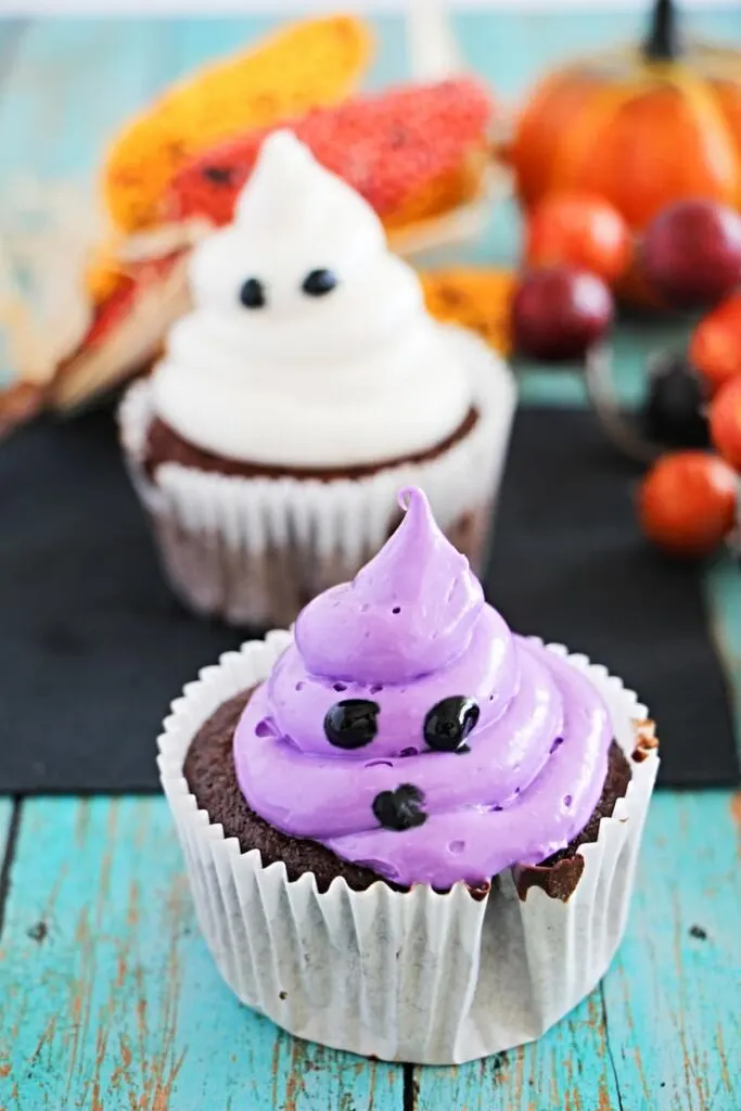 purple ghost cupcake with white ghost cupcake in the blurry background 