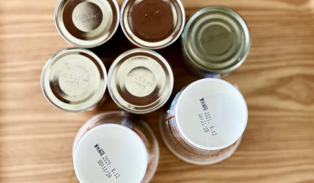 Canned Food and cup noodles showing expiration date on the table