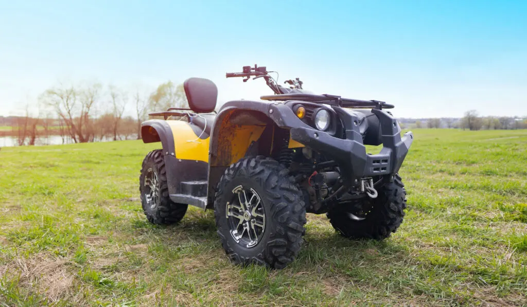 Closeup of ATV on the background of green grass and blue sky 