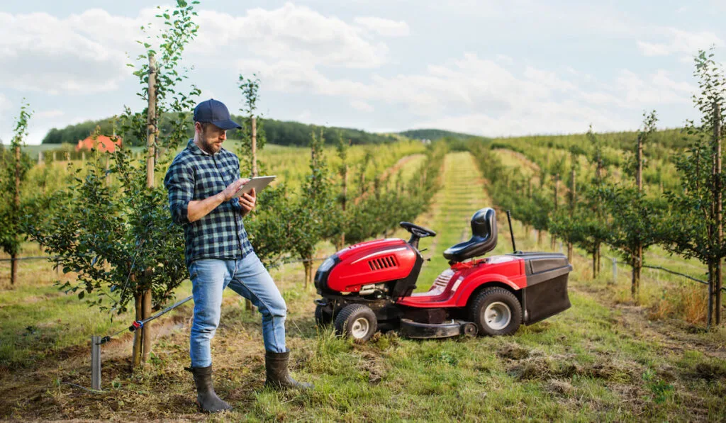 Farmer with his tablet standing in orchard