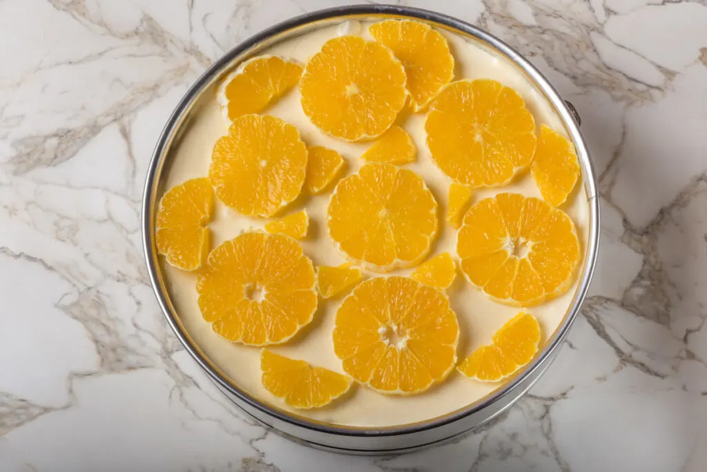 Fresh orange cake in cake pan on a marble table