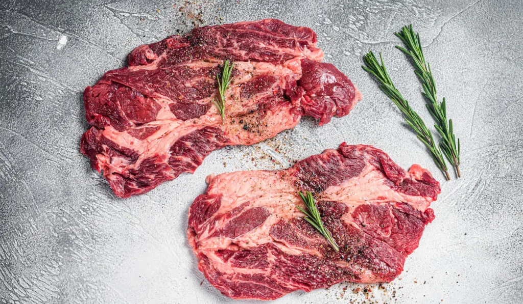 Marbled raw meat Steaks cooking with seasonings and olive oil, fresh beef rib eye steaks.

