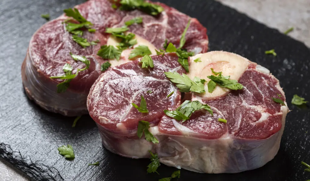 Pieces of raw fresh beef shank with fresh green parsley