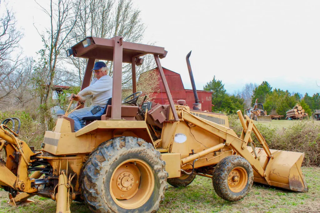 Senior Farmer operating a backhoe on the farm 