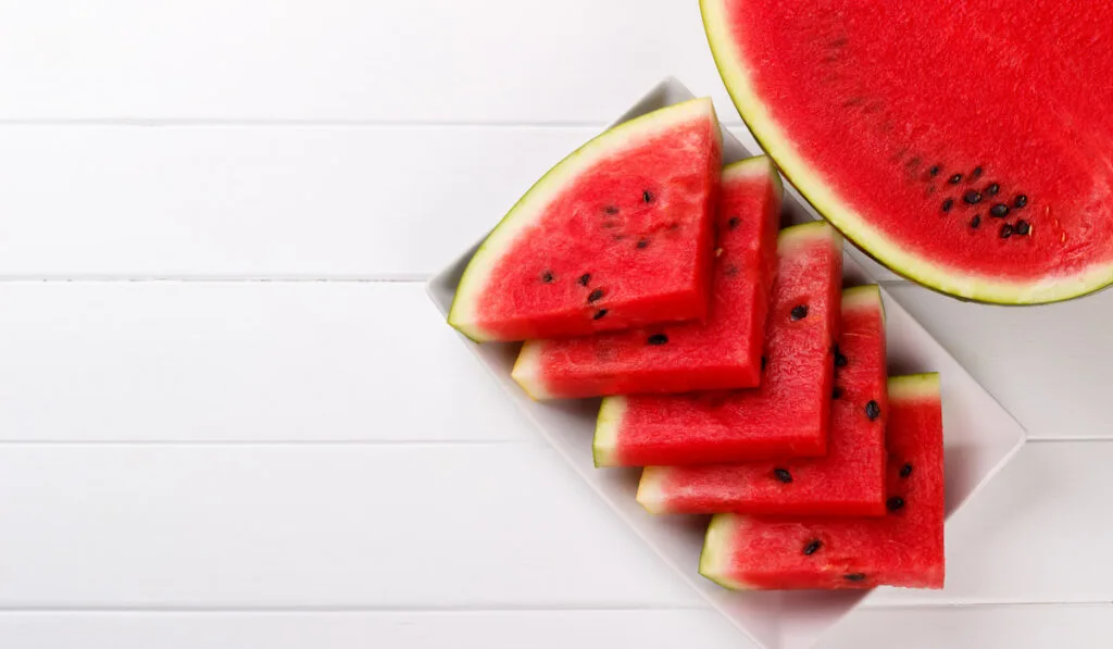 Sliced, juicy watermelon overhead view on a plate on white background