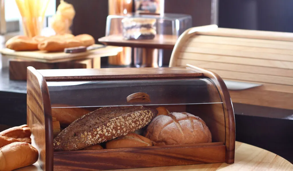 Wooden Breadbox storage Bread Kitchenware with multiple type of breads inside on the table