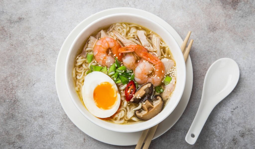 ramen noodle soup with prawn, shiitake mushroms and egg in white bowl