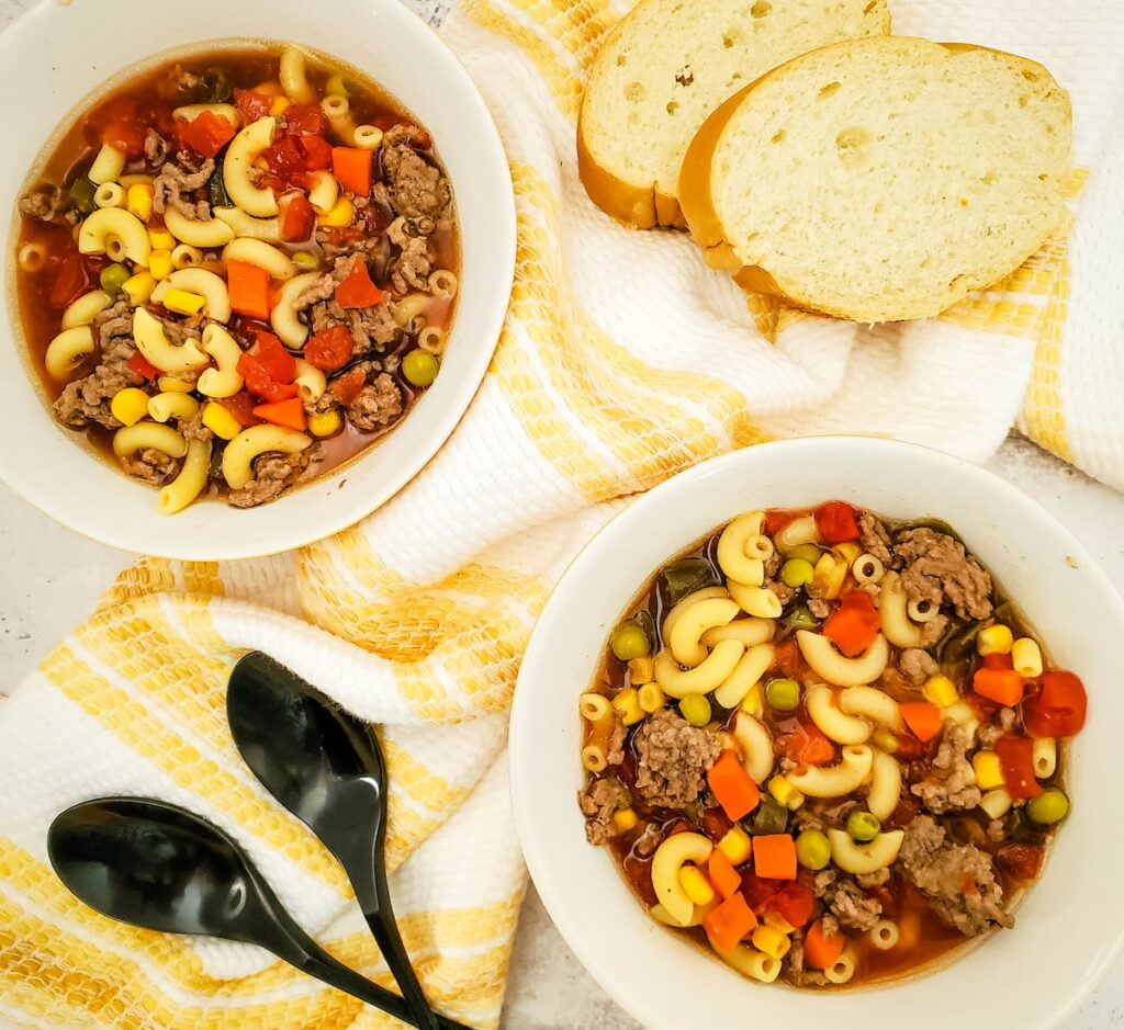 2 bowsl of Crockpot Beef Macaroni Soup laid on table with bread