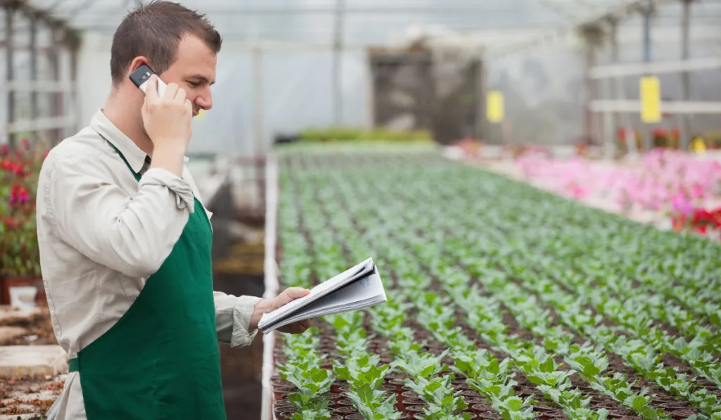 Gardener calling supplier and taking notes