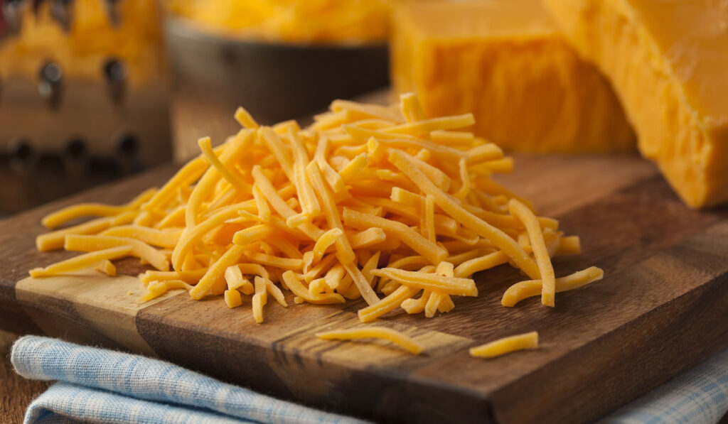 Organic Shredded Sharp Cheddar cheese on a cutting board