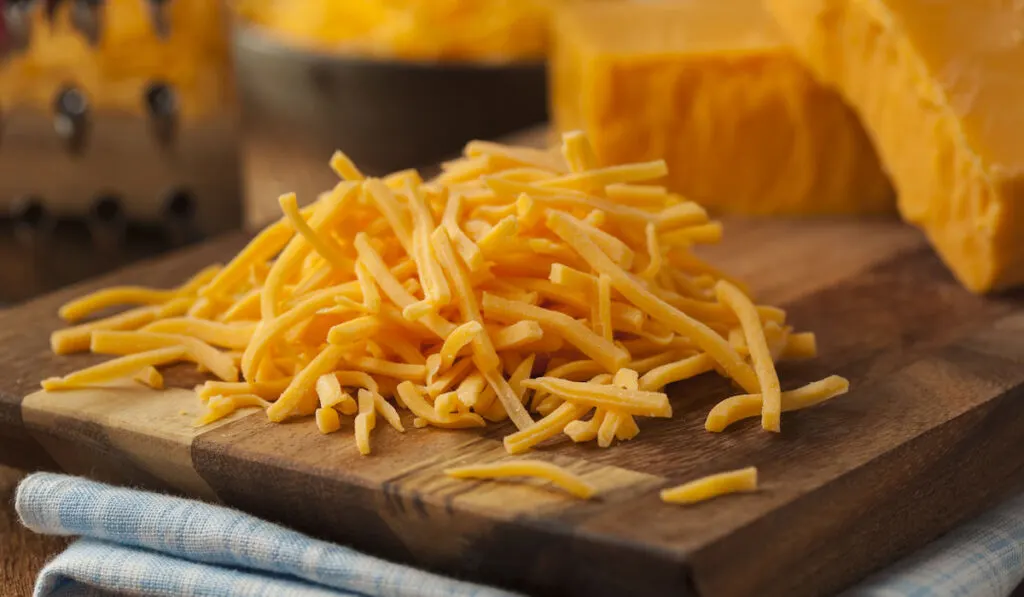 Organic Shredded Sharp Cheddar cheese on a cutting board