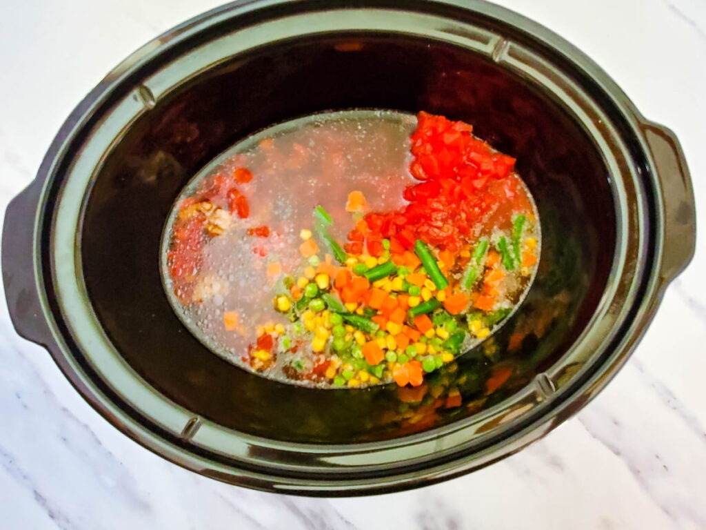 Process 6 broth added to a crockpot with ground beef, mixed veggies, diced tomatoes, salt, and pepper 
