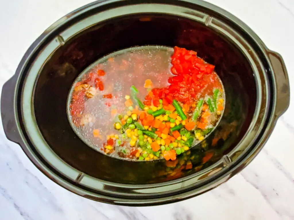 Process 6 broth added to a crockpot with ground beef, mixed veggies, diced tomatoes, salt, and pepper 