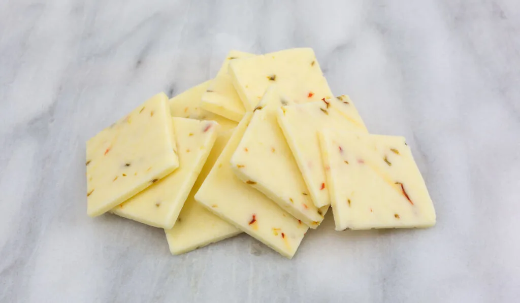 Small pile of fresh pepper jack cheese on a gray marble  cutting board