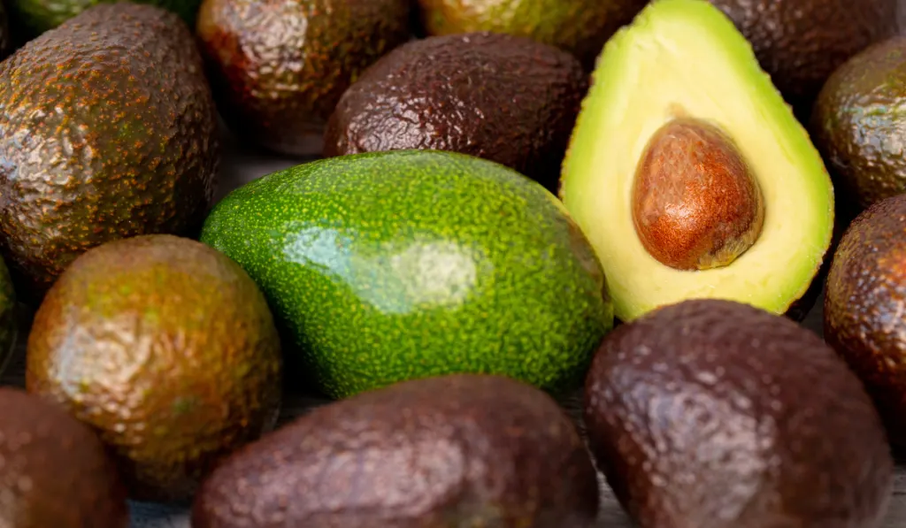 bunch of whole avocado with one sliced open