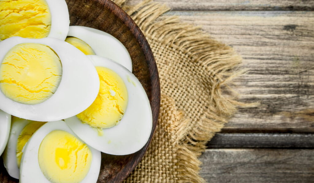 Boiled eggs in bowl on a wooden background