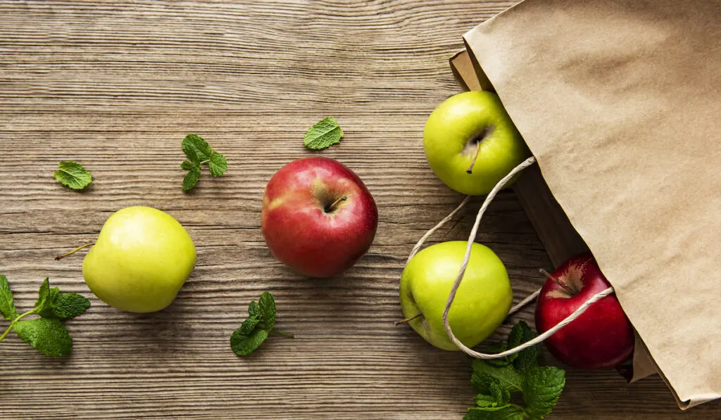 Fresh apples from paper bag on a wooden table