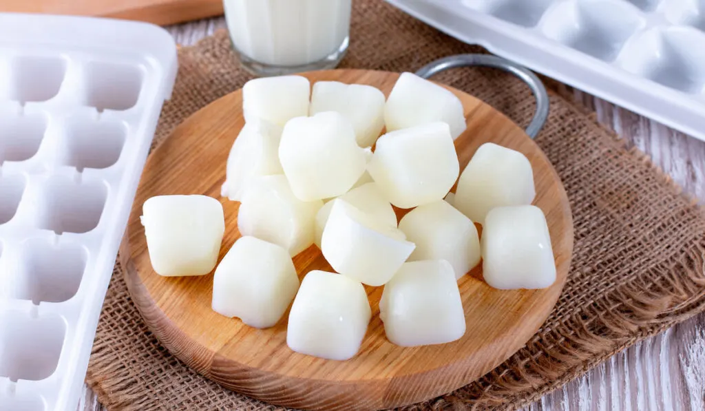 Frozen milk, milk ice cubes on a cutting board 