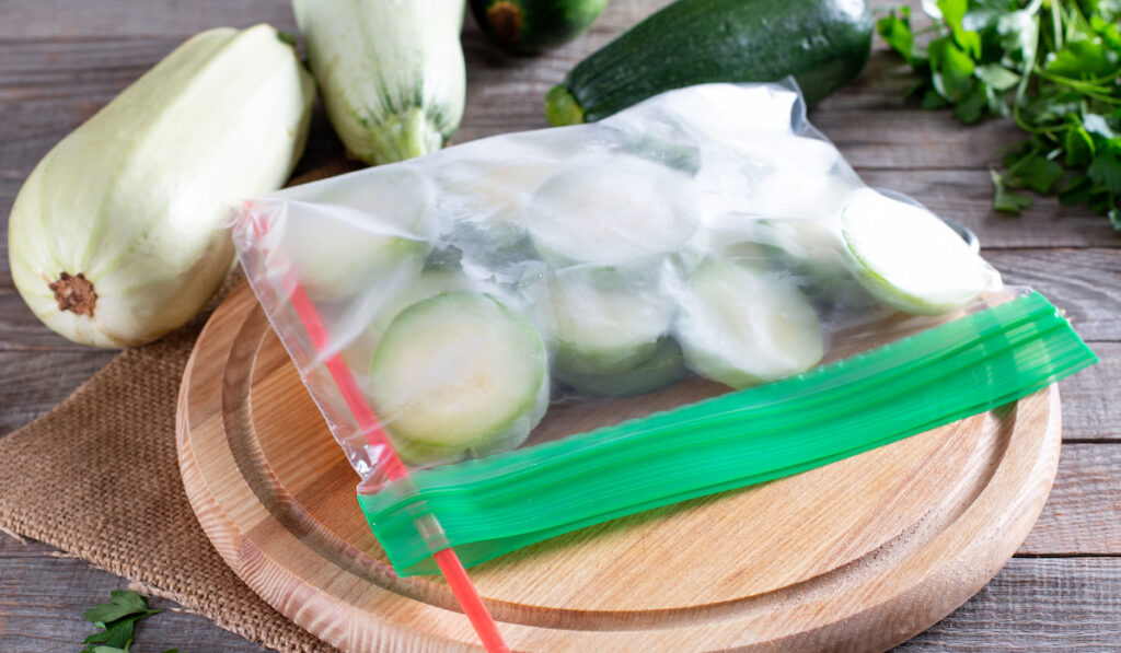 Frozen zucchini in ziplock bag on wooden table
