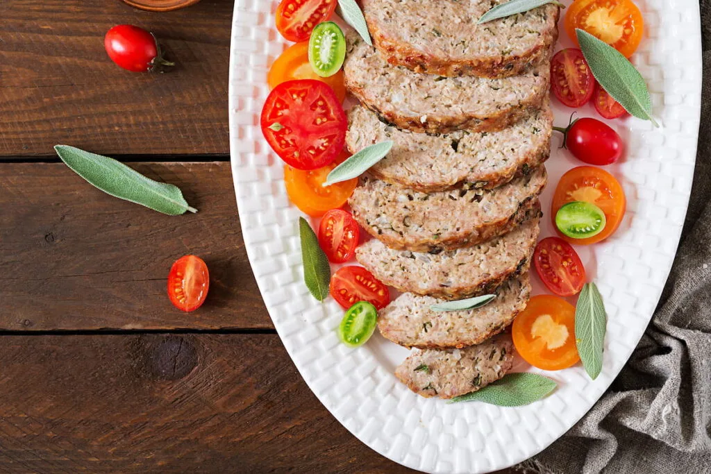 Tasty homemade ground baked turkey meatloaf in white plate on wooden table