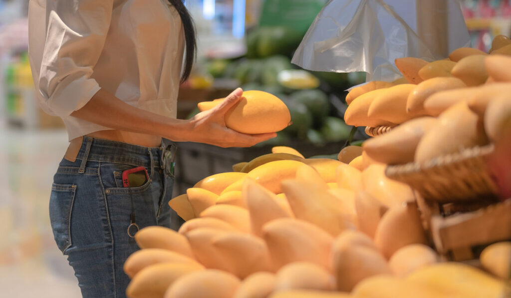 Woman buying fresh mangoes in the supermarket