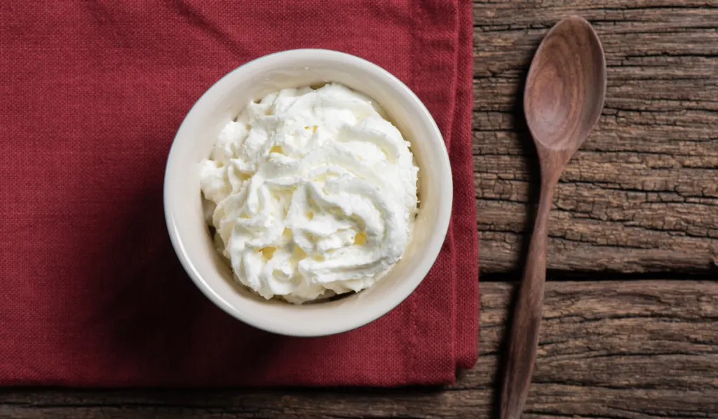 a cup of whipped cream on wooden table
