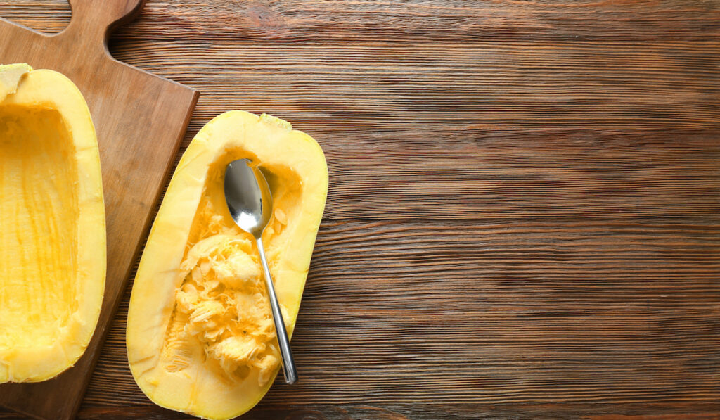 halves of fresh spaghetti squash with spoon on wooden background