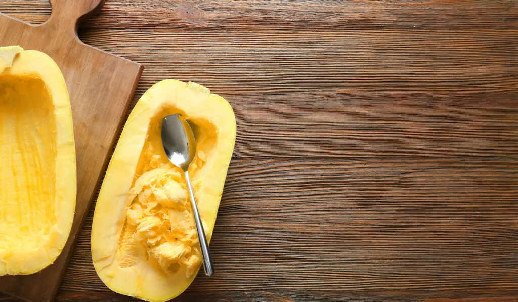 halves of fresh spaghetti squash with spoon on wooden background