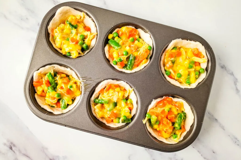Added chicken and veggies filling into muffin cup
