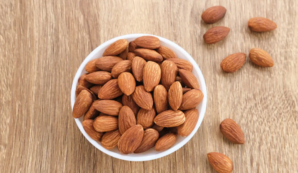 Almond in white bowl on wooden table