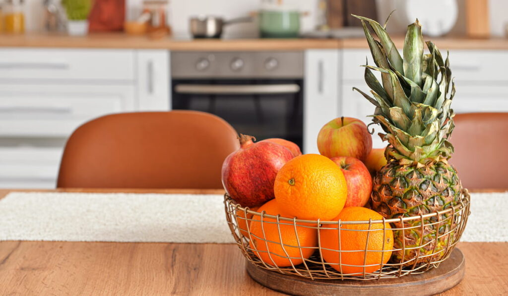 Basket with fresh fruits on wooden table in kitchen 
