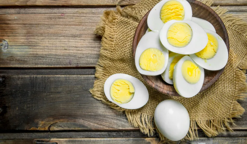 Boiled eggs on wooden plate on wooden background