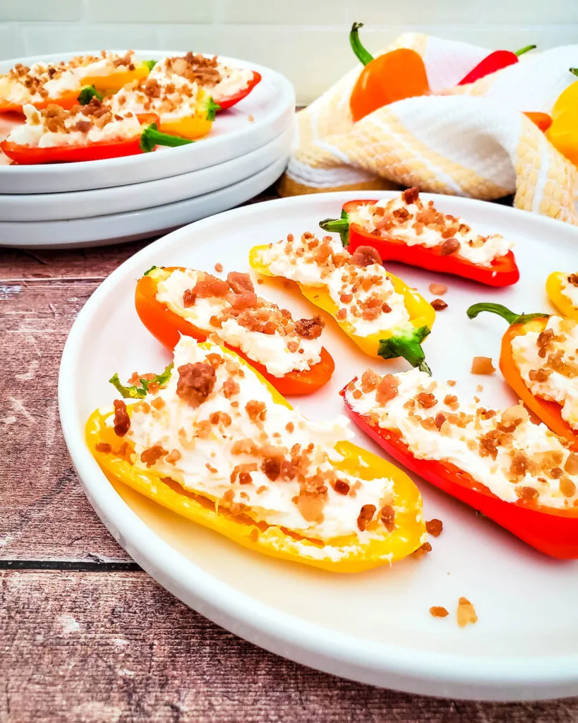 Cheesy bacon stuffed mini peppers on white plate on wooden table