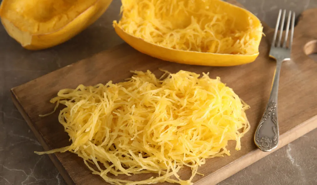 Cooked Spaghetti squash and fork on wooden board