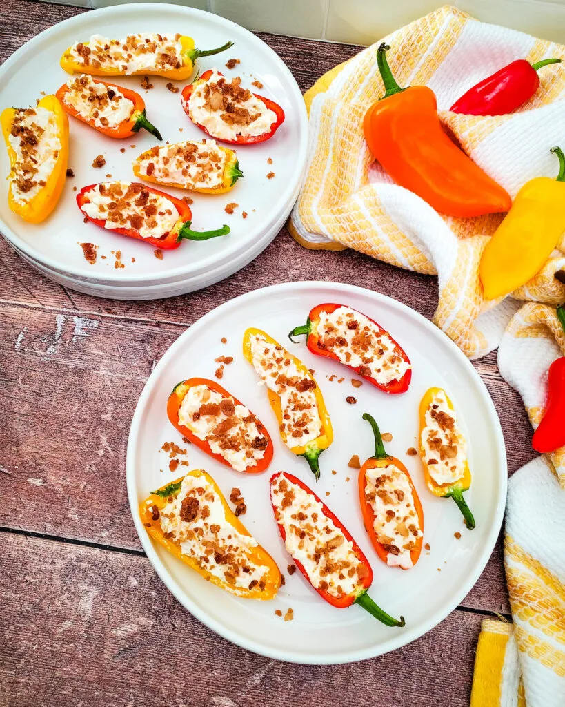 Low carb cheesy bacon stuffed mini peppers on white plates on wooden table