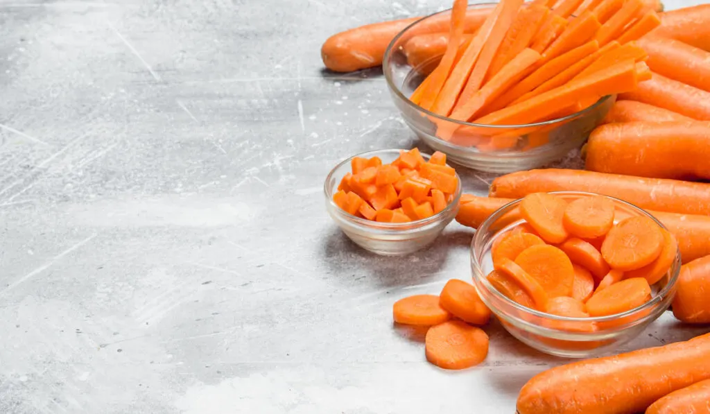 Slices of carrots in a glass bowl on rustic background