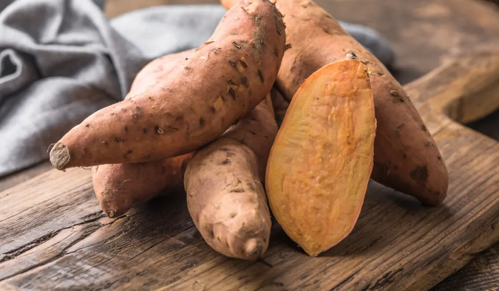 Sweet potato on wooden board on the table