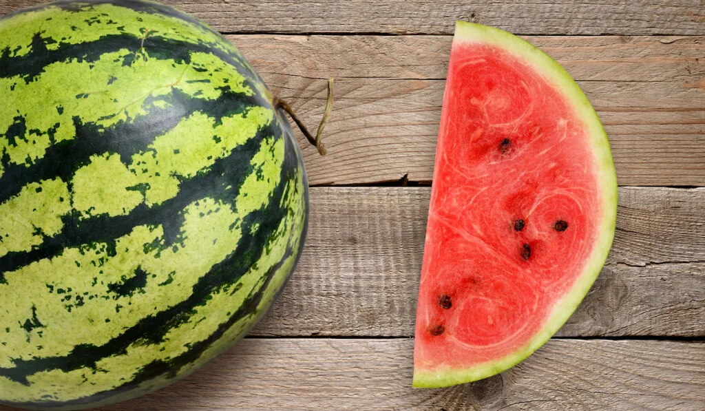 Whole and sliced watermelon on wooden table 