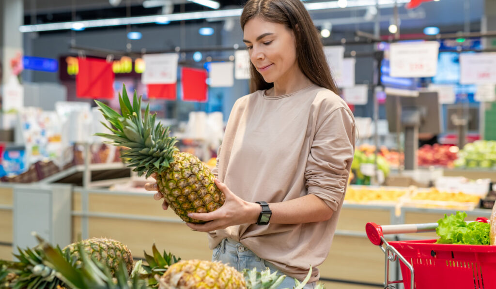 Woman choosing a pineapple in supermarket