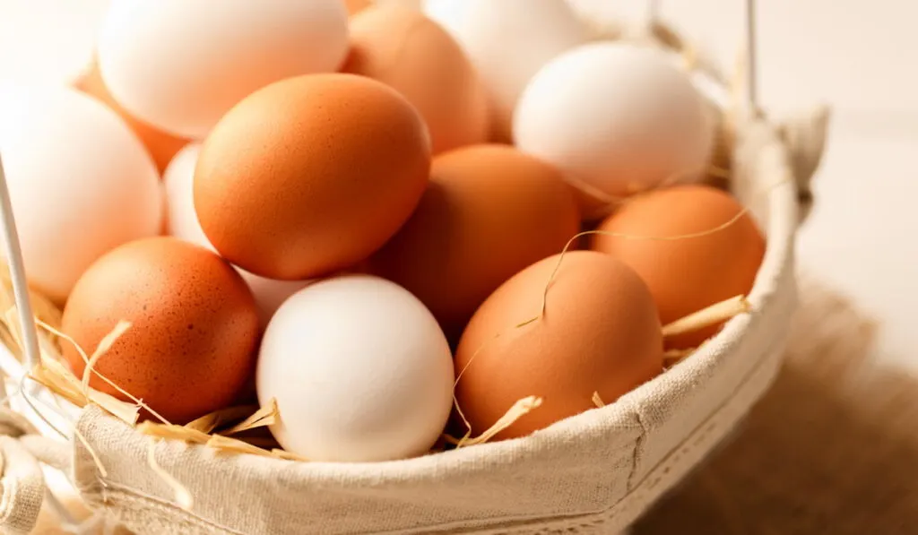 brown and white raw eggs in a basket